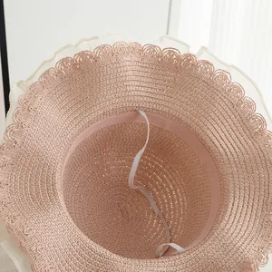Detail eines rosa Strohhuts mit weißem Spitzenbesatz und elastischem Kinnband für Kinder
