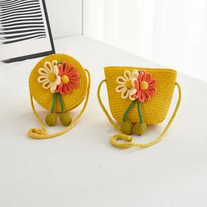 Detail of yellow handmade straw crossbody bags with fabric flowers for little girls