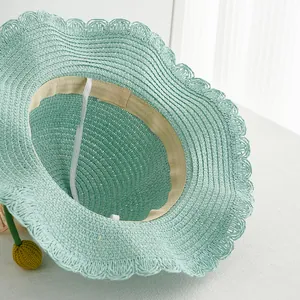 Detail of mint green straw hat with wavy brim, inner sweatband and white windproof rope