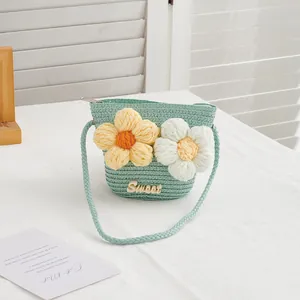 Detail of green straw woven girls bag with large 3D crochet flowers and sweet metal plate