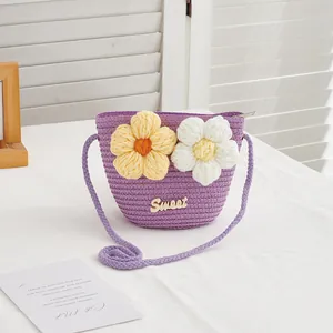 Detail of purple woven girls' straw bag featuring large crochet flowers and Sweet logo