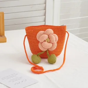 Close-up of orange straw woven crossbody bag with large 3D fabric flower detail