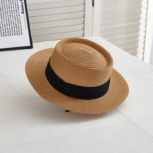 Detailed weave of a boater straw hat with black ribbon in a bright lifestyle setting
