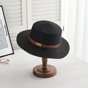 Détails de la texture du chapeau de paille noir avec ruban cuir et boucles dorées