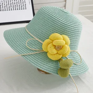 Détail d'un chapeau de paille vert menthe avec fleur jaune et ruban ivoire élégant