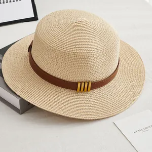 Détail du chapeau de paille avec ruban en cuir brun et boucles en métal doré chic
