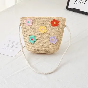 Detail der Strohtasche für Kinder mit bunten Häkelblumen und geflochtenem Seilgurt