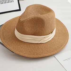 Detail of hand-woven straw jazz hat with wide beige ribbon trim in home setting