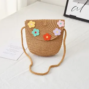 Detail showing colorful crochet flower decorations on straw crossbody bag for girls
