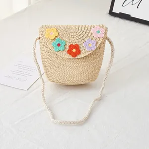 Detail of kids straw crossbody bag featuring handmade colorful crochet flowers on the flap