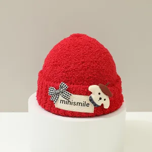 Dettaglio cappello rosso peluche con etichetta minismile, fiocco e toppa cucciolo