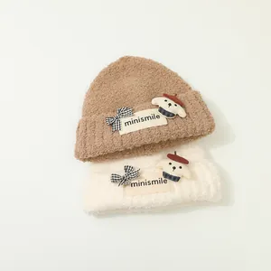 Dettaglio di berretti in maglia peluche con patch minismile e decorazioni a cucciolo 3D
