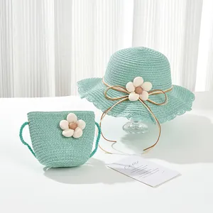 Close-up of kids light green woven straw hat and matching bag with white floral accents