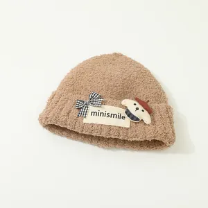 Dettaglio del cappello di peluche marrone con texture orsetto e pendente carino