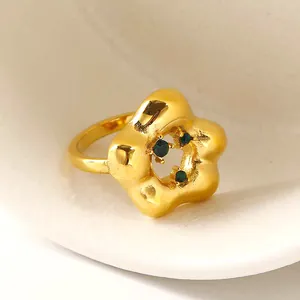 Elegante gouden ring met groene edelstenen en een uniek hol bloemmotief ontwerp