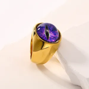 Bague oeil de démon dorée avec pierre violette sur un support en pierre blanche