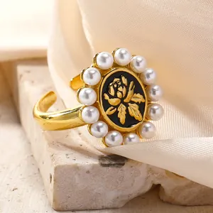 Detail of vintage gold ring with black oval plate, rose relief and pearl trim on satin