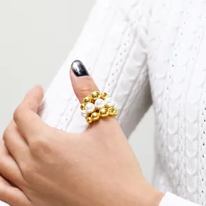 Detailed view of layered gold beads and white pearls ring on a textured knit background