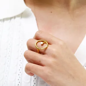 Close-up of minimalist gold titanium steel ring featuring a central white pearl detail