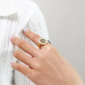 Detail shot of vintage pearl ring with golden floral relief on black dial worn by model