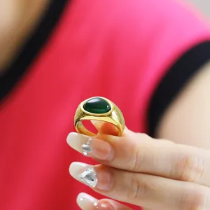 Nahaufnahme eines breiten 18k vergoldeten Rings mit großem ovalen grünen Edelstein auf Hand