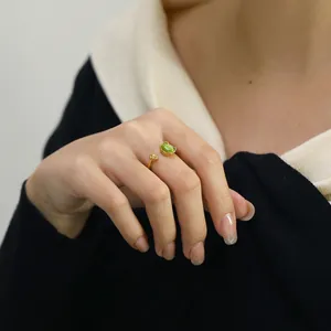 Detail of gold open ring featuring green cat eye stone and delicate flower accent