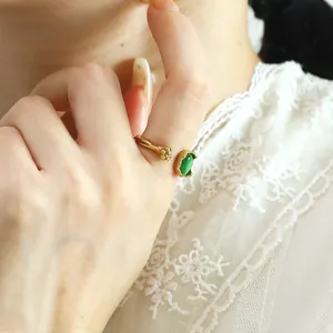 Detail of adjustable gold-plated branch ring with green oval cat eye stone on hand