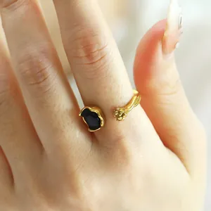 Detail of adjustable gold ring featuring a 3D cat paw and black oval centerpiece