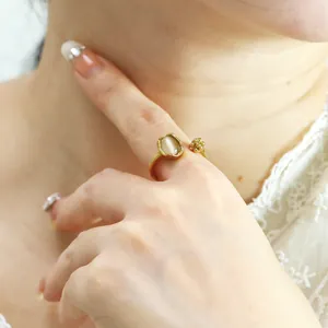 Close-up of gold cat-eye stone ring with floral details on woman's finger