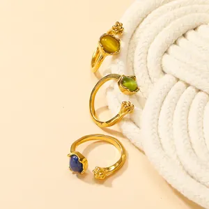 Detailed view of adjustable gold rings with cat eye stones in blue, green and amber tones