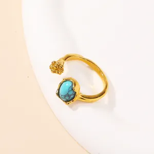 Detail of gold open ring with blue turquoise stone and floral bead cluster