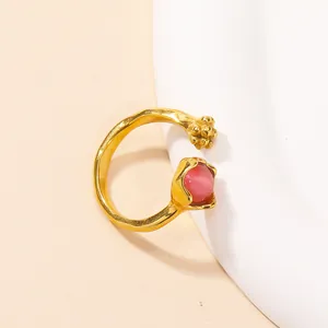 Macro detail of gold-plated cat eye stone ring with floral motif and textured band