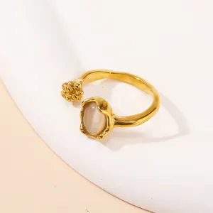 Detailed close-up of a gold open ring with an oval opal stone and small metal clusters