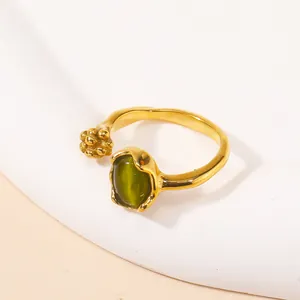 Close-up of golden cat-eye stone ring with green oval gem and beaded metal detail