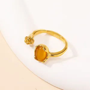 Detail of gold-plated open ring featuring a yellow oval cat eye stone and artistic bead accents