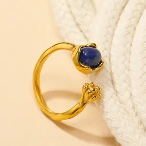 Detailed shot of open cat claw ring featuring dark blue gemstone on a neutral background