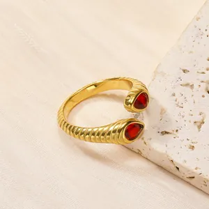 Vue détaillée de la bague en acier doré 18 carats avec texture spirale et zircon rouge