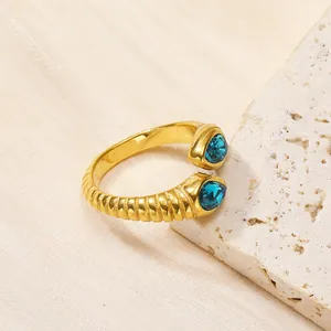Détail d'une bague spirale dorée avec deux zircons bleus en poire sur pierre blanche