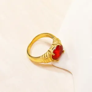 Dettaglio macro dell'anello in titanio dorato con zircone rosso ovale e fascia testurizzata