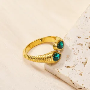 Détail de la bague spirale dorée avec zircon vert poire sur pierre de travertin chic
