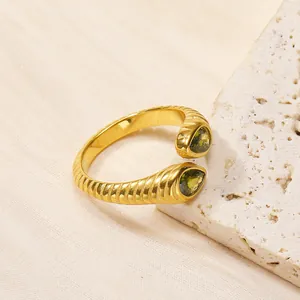 Détail de la bague torsadée dorée avec zircons verts taille poire sur support en pierre