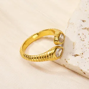 Détail d'une bague ouverte dorée avec zircon poire et texture à rayures horizontales