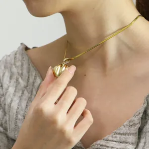 Nahaufnahme einer minimalistischen 18k vergoldeten runden Anhänger-Halskette an einem Model