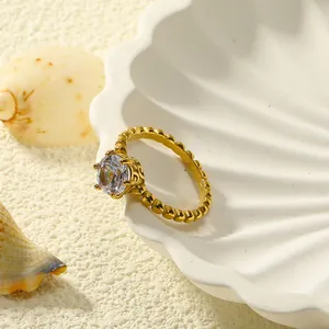 Detail van 18k vergulde titanium ring met kroongezette zirkoon op een schelpdisplay