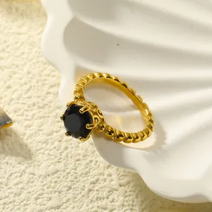 Macro-opname van een 18k vergulde ring met zwarte edelsteen op een schelp en zand