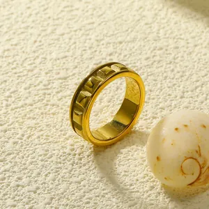 Gouden geometrische roestvrijstalen ring met industrieel reliëf op gestructureerde steen