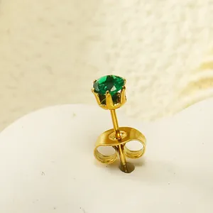 Vue macro d'une boucle d'oreille couronne dorée avec zircon vert et serti à griffes