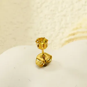 Gros plan d'une puce d'oreille couronne dorée sertie d'un zircon jaune éclatant