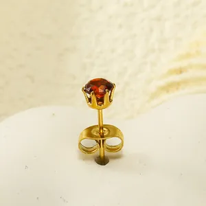 Gros plan détaillé d'une boucle d'oreille couronne dorée avec zircon rouge rond