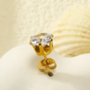 Gros plan d'une boucle d'oreille couronne dorée avec zircon sur un support cœur blanc